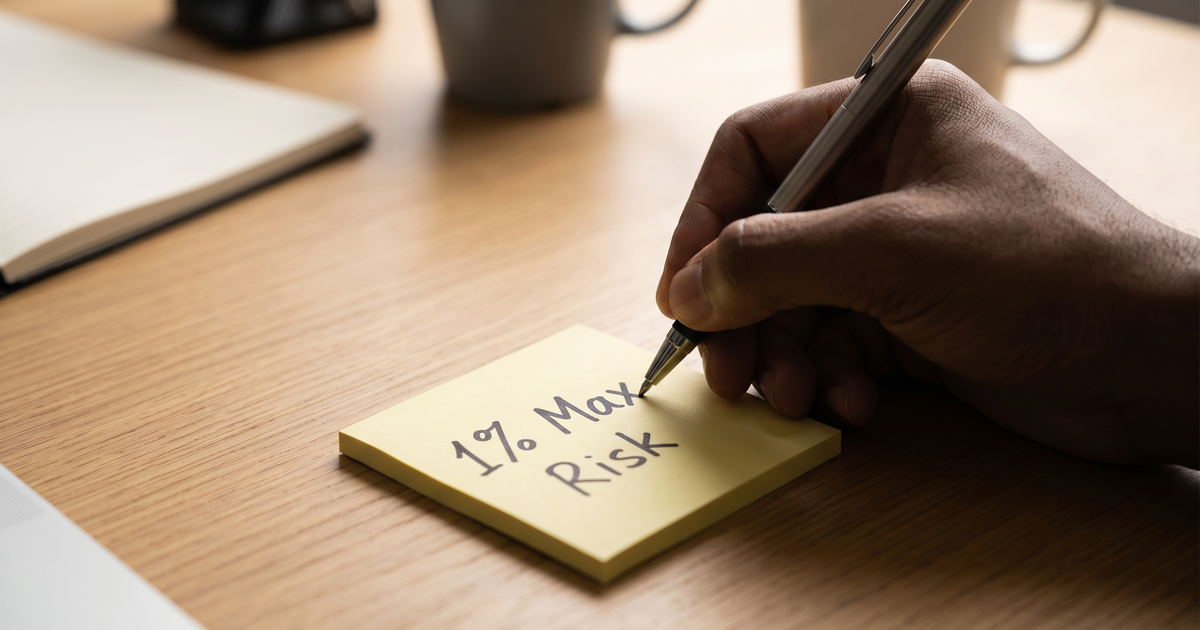 A hand writing 1% Max Risk on a sticky note.